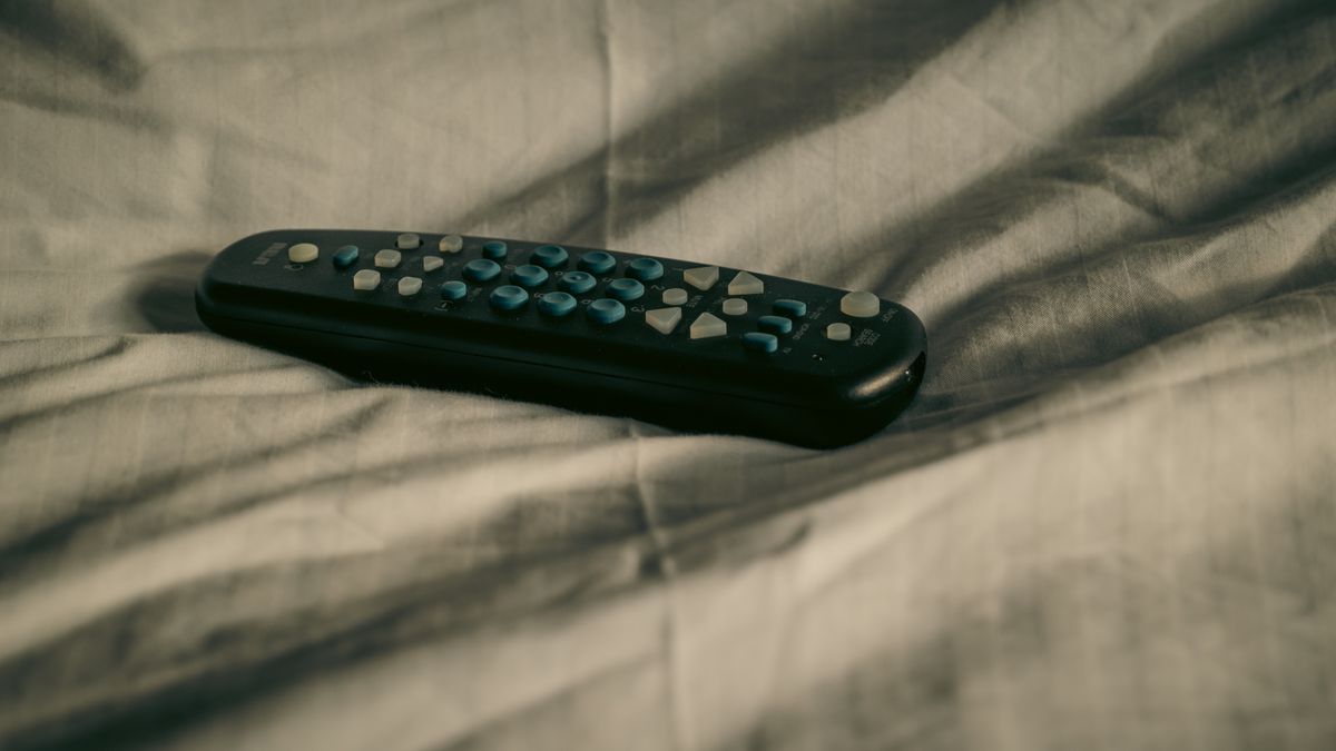 télécommande posée sur un lit, application hot player en soirée